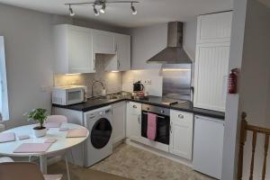cocina con armarios blancos, mesa y microondas en Turtle Dove Apartment, en Oxford
