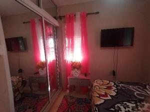 - une chambre avec des rideaux roses, un lit et une télévision dans l'établissement Apartamento K de 3 a 5 Minutos de la embajada, à Pantoja