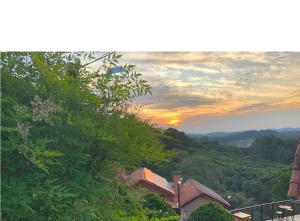 una puesta de sol en las montañas con una casa y árboles en Pousada Cerejeiras, en Monte Verde