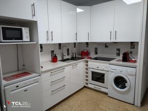 cocina con armarios blancos, lavadora y secadora en Casa Maya en Maspalomas