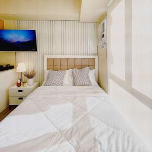 um quarto com uma grande cama branca e uma televisão em Cebu City Scape at Cebu IT Park em Cebu
