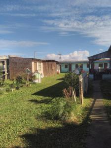 einen Hof mit Häusern, einem Zaun und Gras in der Unterkunft Pousada do bololo in Cidreira