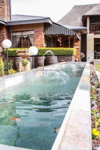 une piscine en face d'une maison avec une fontaine dans l'établissement Siesta Guesthouse & Wedding Venue - Frankfort, à Frankfort