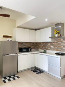 a kitchen with white cabinets and a stainless steel refrigerator at AZURE Urban Resort Residences Condominium in Manila