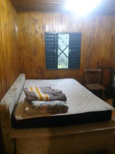 Una cama en una habitación de madera con toallas. en Sítio lageana, en Gramado