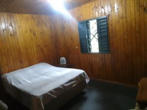 1 dormitorio con cama y ventana en Sítio lageana, en Gramado