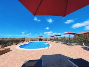 a swimming pool with umbrellas and a blue sky at Il Melarancio in Pescia Romana