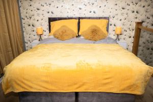 1 dormitorio con 1 cama con sábanas amarillas y 2 lámparas en Cozy modern house, exotic garden and King size bed en Fallings Park