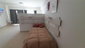 a bed in a room with a wall at Amplio Estudio de lujo con balcon y parrilla in Puerto Madryn