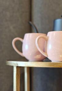 dos tazas rosas sentadas sobre una estantería de madera en St Hugh Hotel Wagga Wagga, en Wagga Wagga
