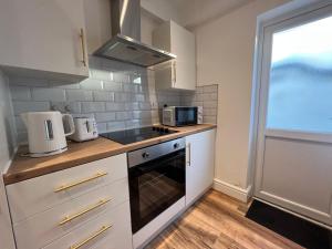 a kitchen with white cabinets and a stove and a window at Liverpool Cherry House - 4 Bedrooms in Liverpool