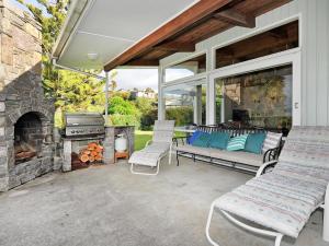 a patio with a fireplace and a couch and chairs at Kereru at Kaiteriteri - Kaiteriteri Holiday Home in Kaiteriteri