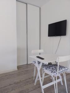 a white table and chair with a television on a wall at Aires de mar in San Clemente del Tuyú