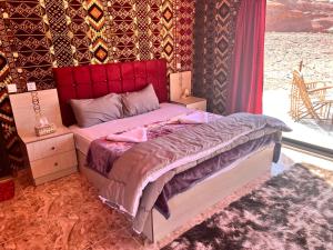 a bedroom with a bed with a red headboard at Wadi Rum Sky Tours & Camp in Wadi Rum