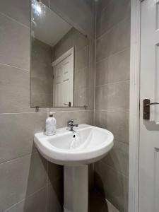 uma casa de banho com um lavatório branco e um espelho. em Liverpool Cherry House - 4 Bedrooms em Liverpool