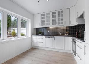 a white kitchen with white cabinets and windows at 5-Bedroom Apartment in Åsane, Bergen in Bergen