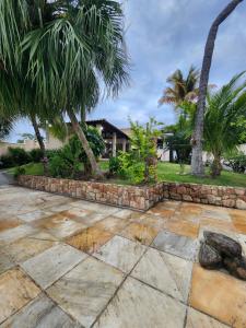 a yard with palm trees and a stone wall at Casa na Lagoa in Maricá