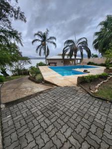 una pasarela de piedra que conduce a una piscina con palmeras en Casa na Lagoa en Maricá