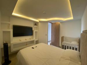 a bedroom with a bed and a flat screen tv at Hermoso apartamento a solo 15 minutos del parque del cafe in Montenegro