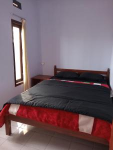 een bed in een slaapkamer met een rode witte en zwarte deken bij Mentigen Homestay in Ngadisari