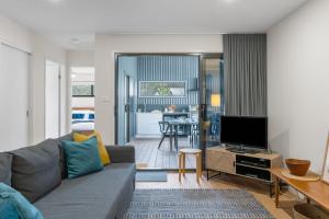 a living room with a gray couch and a television at Coastal Retreat in Kioloa