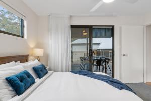 1 dormitorio con cama blanca y almohadas azules en Coastal Retreat en Kioloa
