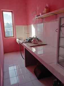 una cocina roja con encimera y hervidor de agua. en Mentigen Homestay en Ngadisari