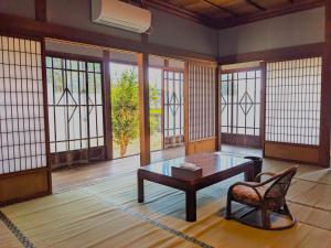 um quarto com uma mesa, uma cadeira e janelas em 和風ホテル鳴門家族連れにおすすめの和室でのんびり滞在できる宿 em Naruto