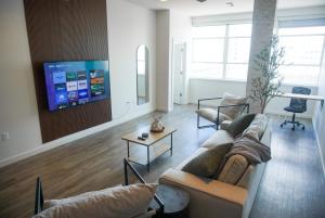 sala de estar con 2 sofás y TV de pantalla plana en Entire High-Rise Apartment - 2BD en Baton Rouge