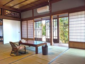 una camera con tavolo, sedia e finestre di ステイ和屋Ooasa徳島で家族とのんびりできる和室宿 a Naruto