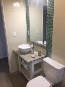 ein Badezimmer mit einem Waschbecken, einem WC und einem Spiegel in der Unterkunft La Toscana 1 in Piriápolis