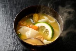 a bowl of soup with vegetables and a lime at Hotel Forza Oita in Oita