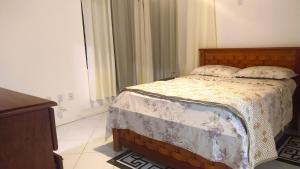 a bedroom with a bed and a dresser at Suite Fogo - A Casa 9 Lilás em Barra de Jacuipe in Camaçari