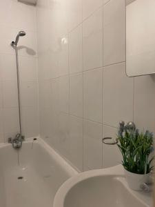 a white bathroom with a tub and a plant at Stratford Guest House By Cosystays in London