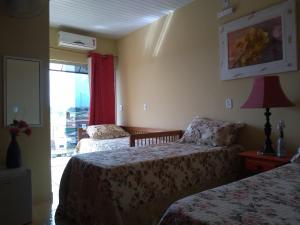 une chambre d'hôtel avec deux lits et une fenêtre dans l'établissement Pousada São João Batista, à Cachoeira Paulista