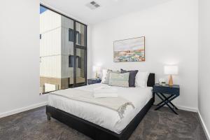 a bedroom with a large bed and a window at Urban Rest Port Adelaide Apartments in Port Adelaide