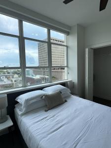 a white bed in a room with a large window at Stylish Downtown High-Rise - 2BD in Baton Rouge