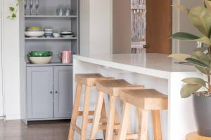 a kitchen with a white counter and stools at Cosy Corner Hideaway in Torquay