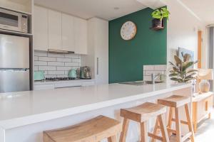 a kitchen with a counter with stools and a clock on the wall at Cosy Corner Hideaway in Torquay