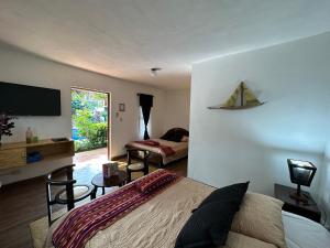 1 dormitorio con 1 cama y TV en la pared en Hotel Atelie del Mar, en Monterrico