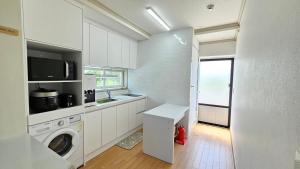 a white kitchen with a washing machine and a window at Someday Jeju in Jeju