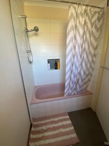 a bathroom with a tub with a shower curtain at Doncaster Westfield Home Stay in Doncaster +7 photos