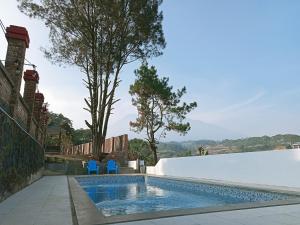 a swimming pool with two blue chairs next to a wall at Villa Forest Puncak in Tagalbato