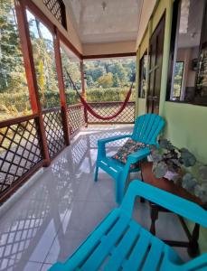 a balcony with two blue chairs and a view at Casa Farolito in Hone Creek
