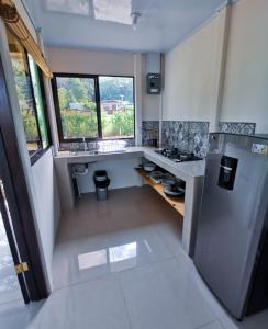 a small kitchen with a refrigerator and a window at Casa Farolito in Hone Creek