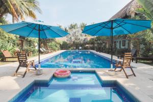 a swimming pool with two chairs and two umbrellas at Hotel Atelie del Mar in Monterrico