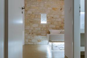 a room with a bed and a stone wall at Aegean Feelings in Piso Livadi