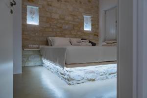a bedroom with a large bed and a stone wall at Aegean Feelings in Piso Livadi