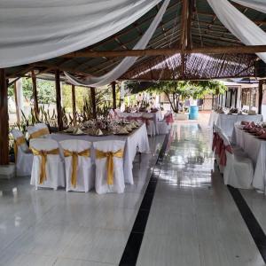 una fila de mesas en un pabellón con mesas blancas y arcos amarillos en HOTEL EL RUBY, en San Martín