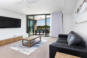 a living room with a black leather couch and a tv at Solaris 410 in Forster